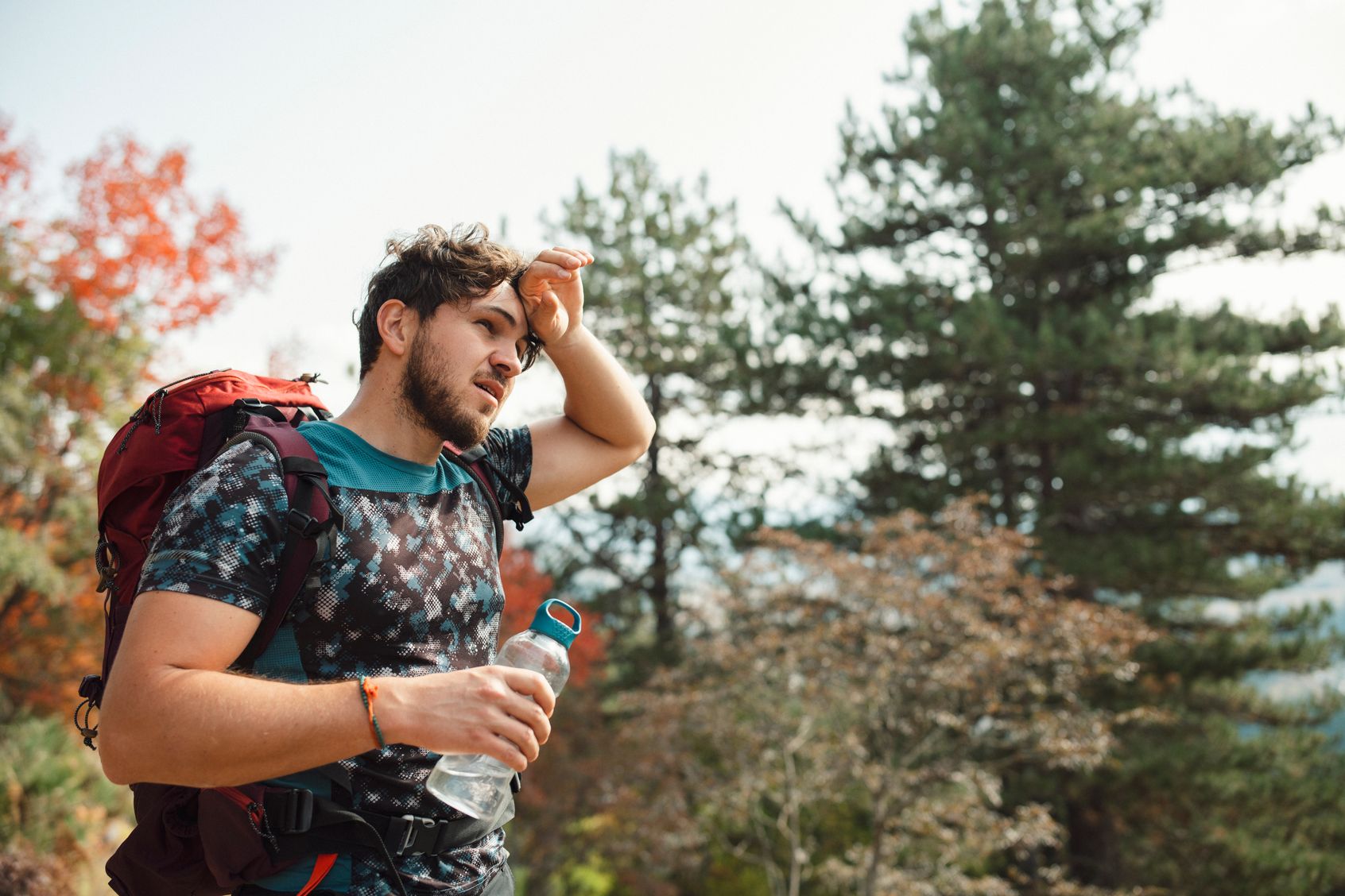 Man with backpack experiencing heat stroke symptoms