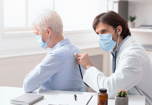 A doctor using a stethoscope on an elderly patient to detect interstitial lung disease