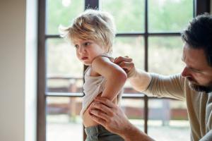 Father checking toddler's back for a rash
