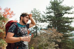 Man with backpack experiencing heat stroke symptoms